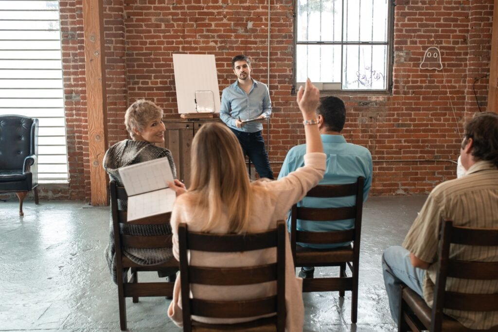 An informal group session, one participant raising a hand to speak.