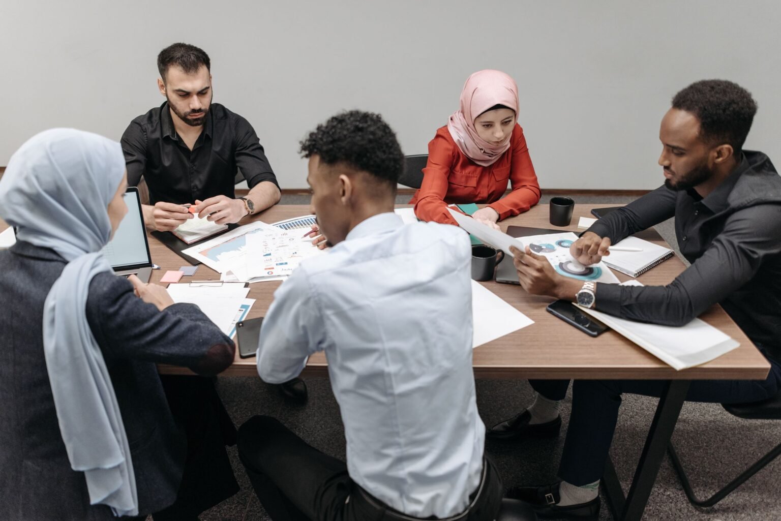 A multinational team working together over documents at a shared table.
