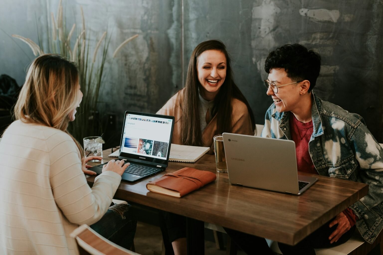 Three colleagues from different countries working together over a laptop and notebooks.