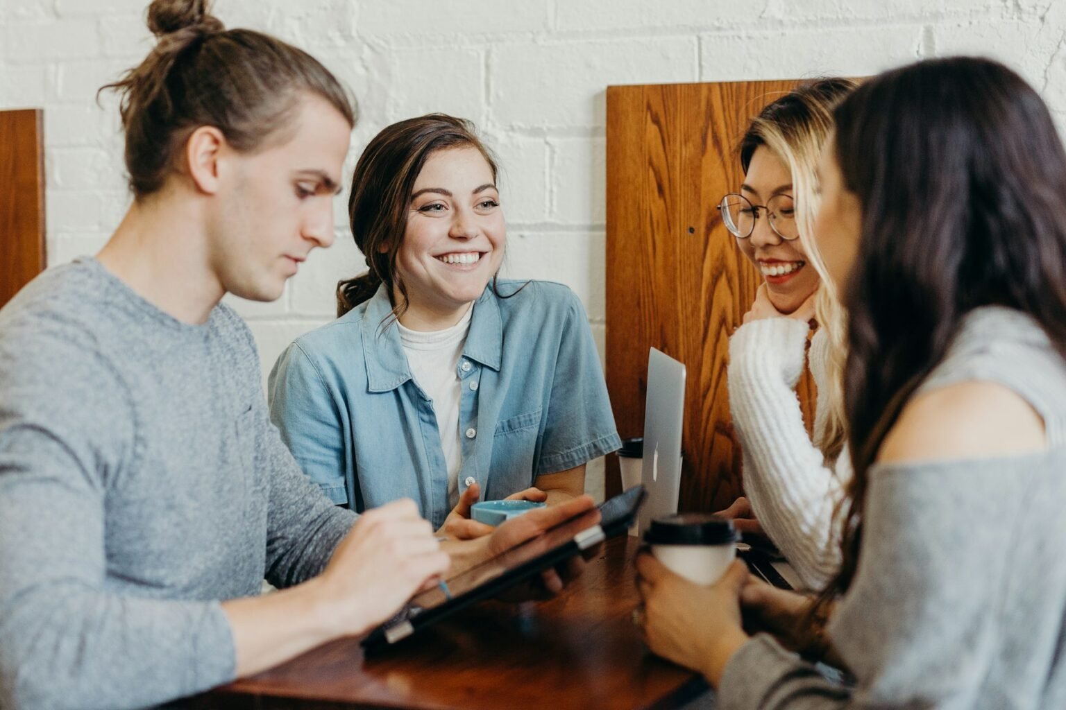 Three colleagues talking over a tablet in a bright meeting space.